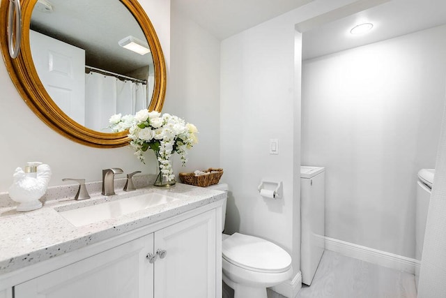 bathroom featuring toilet, baseboards, vanity, and independent washer and dryer