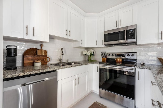 kitchen featuring stainless steel appliances, a sink, tasteful backsplash, and stone counters