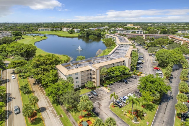 bird's eye view of a nearby body of water, apartment complex, and a tree filled landscape