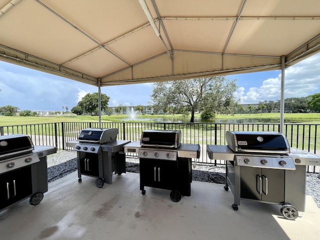 view of patio / terrace featuring area for grilling, a water view, and fence