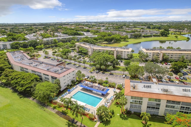 bird's eye view of apartment complex, a nearby body of water, and a pool area