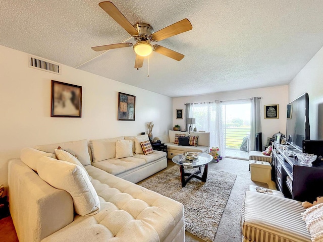 carpeted living area featuring a textured ceiling and a ceiling fan