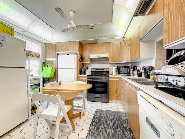 kitchen with white appliances, under cabinet range hood, light countertops, ceiling fan, and light brown cabinetry