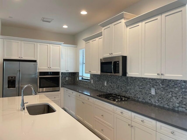 12913 Alton Rd, Palm Beach Gardens, FL 33418 - kitchen featuring appliances with stainless steel finishes, a sink, tasteful backsplash, recessed lighting, and white cabinetry
