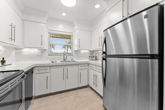 kitchen featuring freestanding refrigerator, a sink, light countertops, ornamental molding, and electric range