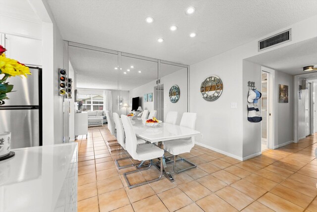 dining area with light tile patterned floors, a textured ceiling, recessed lighting, and baseboards