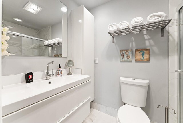 bathroom with toilet, marble finish flooring, a stall shower, and vanity