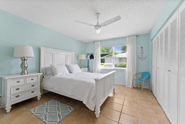 bedroom featuring a closet, light tile patterned floors, a textured ceiling, and a ceiling fan