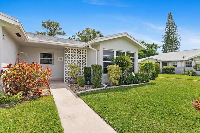 view of front of house featuring stucco siding and a front lawn