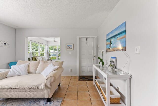 living room with a textured ceiling, light tile patterned floors, and baseboards