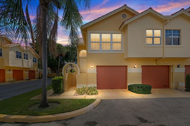 multi unit property with driveway, stucco siding, and an attached garage