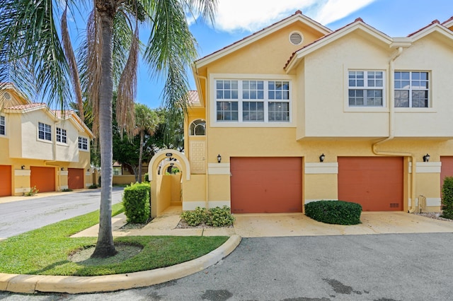 townhome / multi-family property featuring an attached garage, stucco siding, and driveway