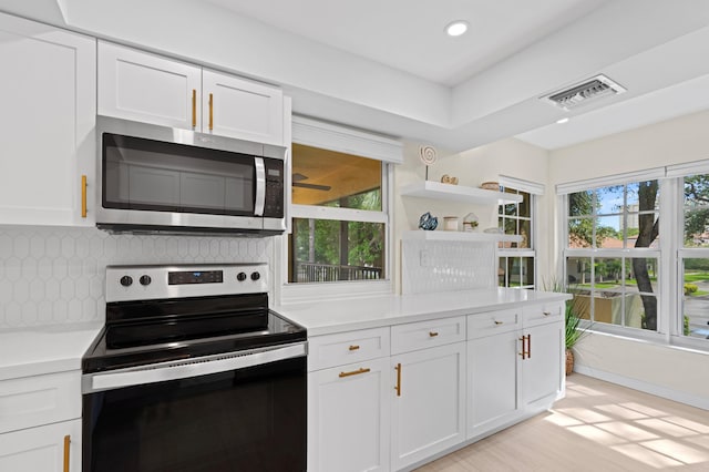 kitchen with stainless steel appliances, visible vents, white cabinetry, decorative backsplash, and light countertops