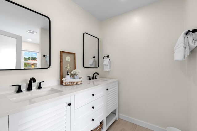 bathroom featuring a sink, double vanity, baseboards, and visible vents