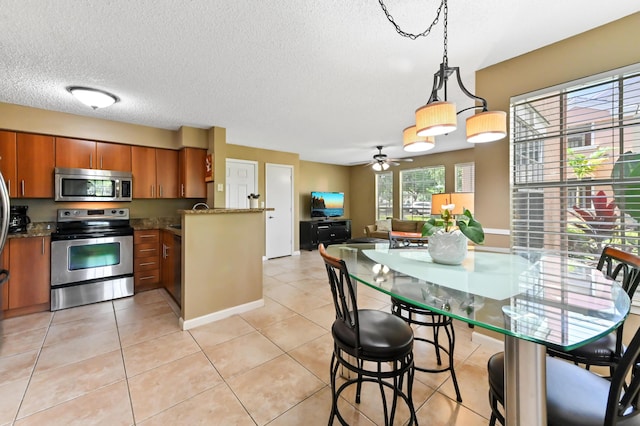 1125 Crystal Way Unit I, Delray Beach, FL 33444 - kitchen with stainless steel appliances, brown cabinetry, ceiling fan, a textured ceiling, and dark stone counters