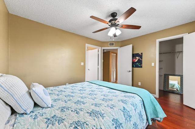 1125 Crystal Way Unit I, Delray Beach, FL 33444 - bedroom featuring wood finished floors, a walk in closet, a closet, a ceiling fan, and a textured ceiling