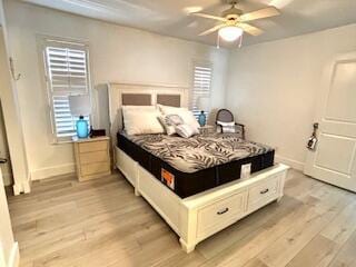 bedroom featuring baseboards, multiple windows, and light wood-type flooring