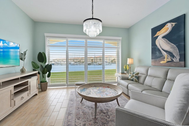 living room with a chandelier, light wood-style floors, and a water view