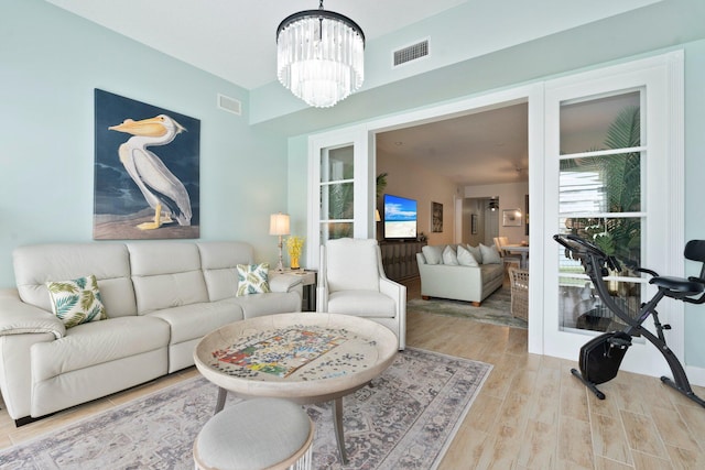 living room with an inviting chandelier, visible vents, and light wood-style flooring