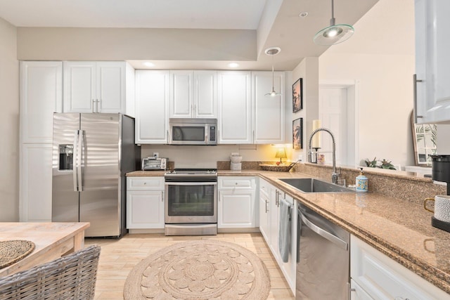 kitchen with a sink, white cabinets, stone countertops, and appliances with stainless steel finishes