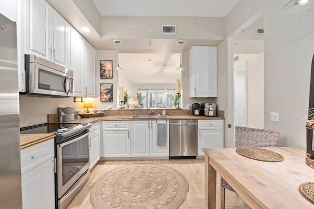 kitchen with white cabinets, appliances with stainless steel finishes, visible vents, and a sink