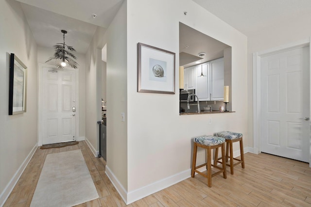 corridor with light wood-type flooring and baseboards