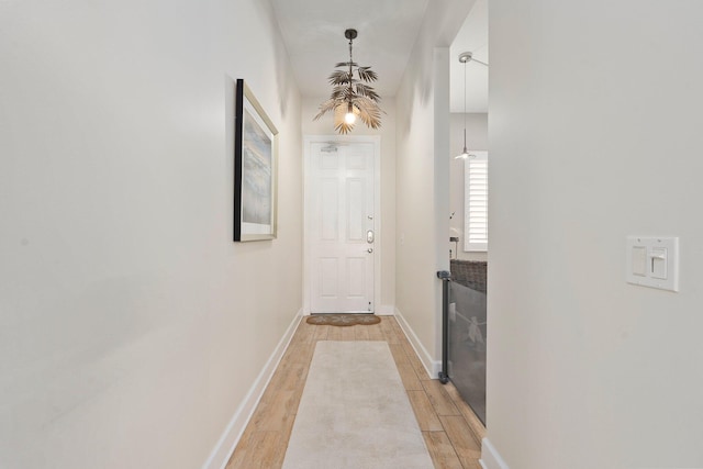 hall with baseboards and light wood-style floors