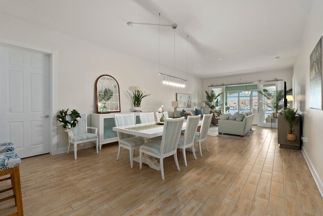 dining room featuring light wood-type flooring, a chandelier, and baseboards