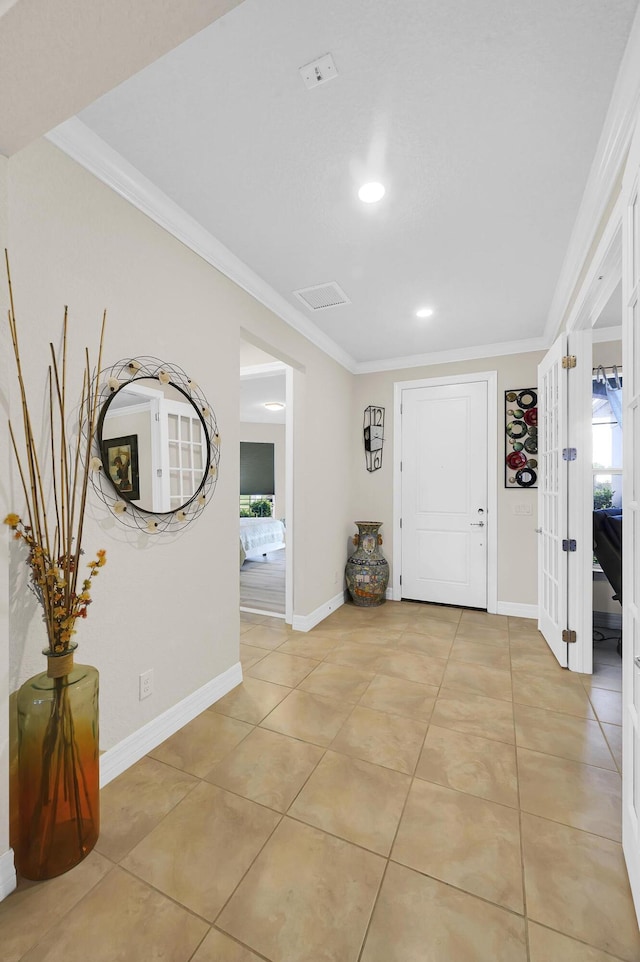 foyer entrance featuring a wealth of natural light, light tile patterned floors, baseboards, and ornamental molding