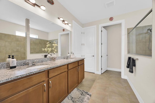 full bathroom featuring double vanity, baseboards, tiled shower, and a sink