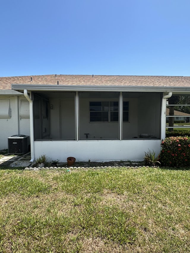 933 Savannas Point Dr Unit C, Fort Pierce, FL 34982 - back of property with central air condition unit, a sunroom, a shingled roof, and a lawn