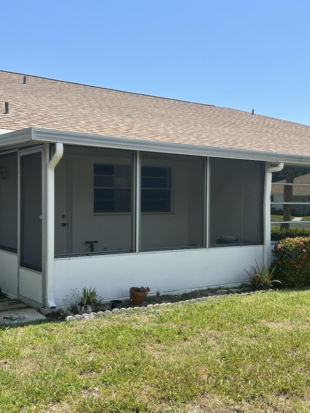933 Savannas Point Dr Unit C, Fort Pierce, FL 34982 - view of side of home with a sunroom, roof with shingles, and a lawn