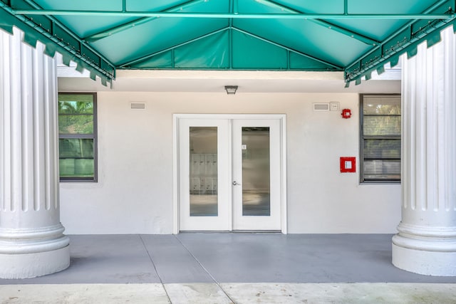 view of exterior entry featuring stucco siding, french doors, and visible vents