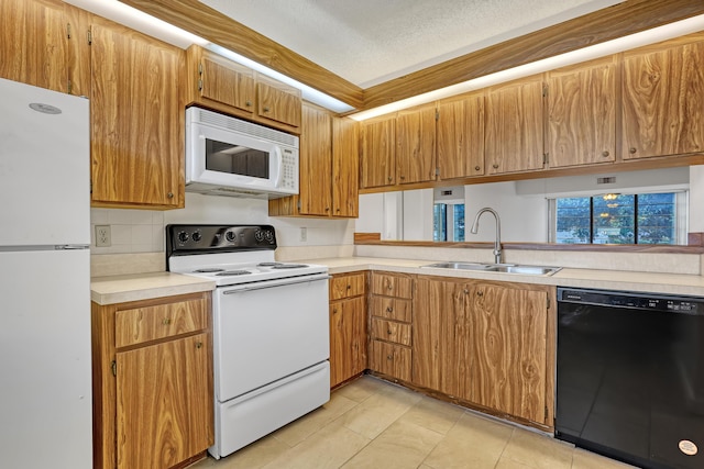 kitchen featuring a sink, white appliances, backsplash, light countertops, and light tile patterned floors
