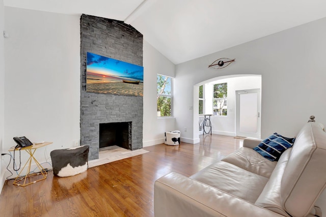 430 NE 121st St, Biscayne Park, FL 33161 - living area featuring lofted ceiling, baseboards, a stone fireplace, wood finished floors, and arched walkways