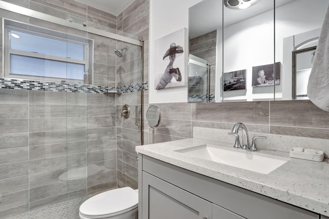 full bath featuring a shower stall, tile walls, vanity, and toilet
