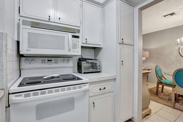 kitchen featuring white appliances, light countertops, light tile patterned flooring, white cabinetry, and decorative backsplash