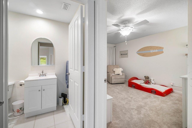 bathroom with vanity, ceiling fan, and a textured ceiling