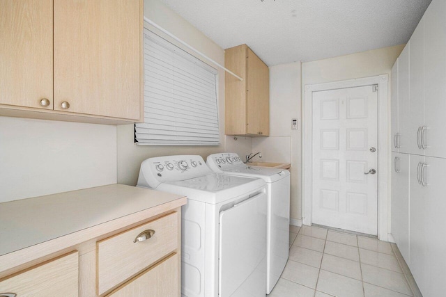 laundry area featuring washing machine and clothes dryer, cabinet space, and light tile patterned floors