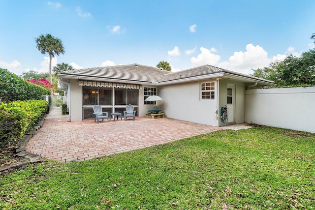 back of house with fence, a patio area, a tile roof, stucco siding, and a lawn