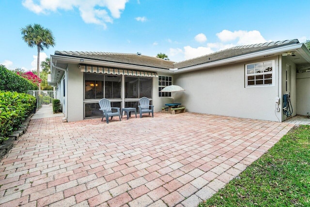back of property with a patio area, stucco siding, a sunroom, and fence