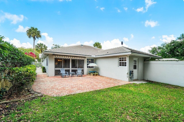 back of property featuring a tiled roof, stucco siding, fence, and a lawn