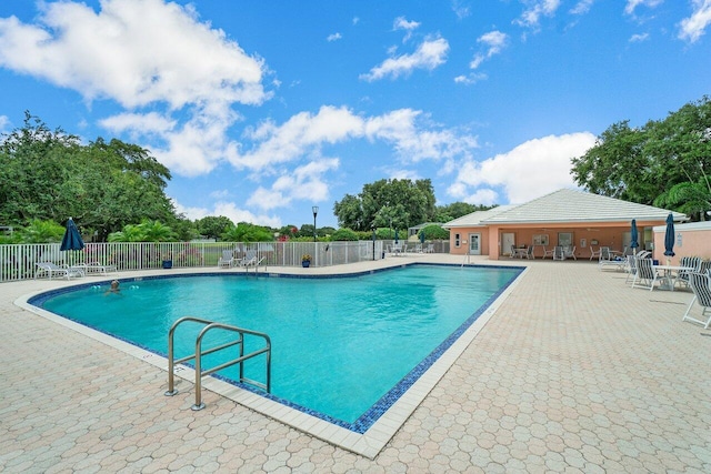 community pool with a patio and fence