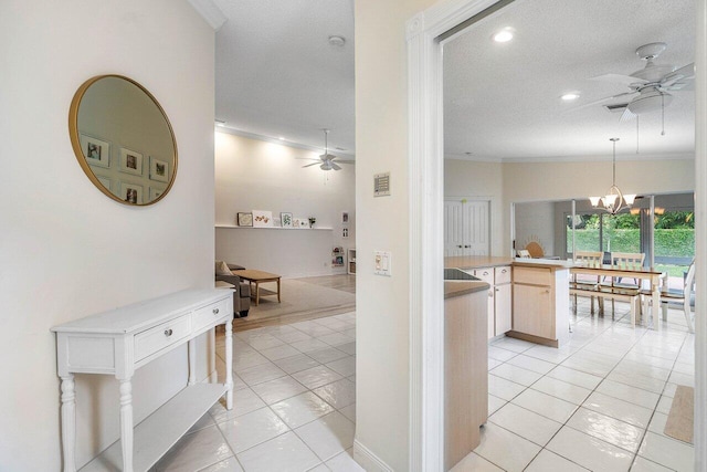 hall featuring light tile patterned flooring, a textured ceiling, recessed lighting, a chandelier, and crown molding