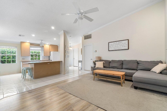 living room featuring crown molding, visible vents, light wood-style flooring, and ceiling fan