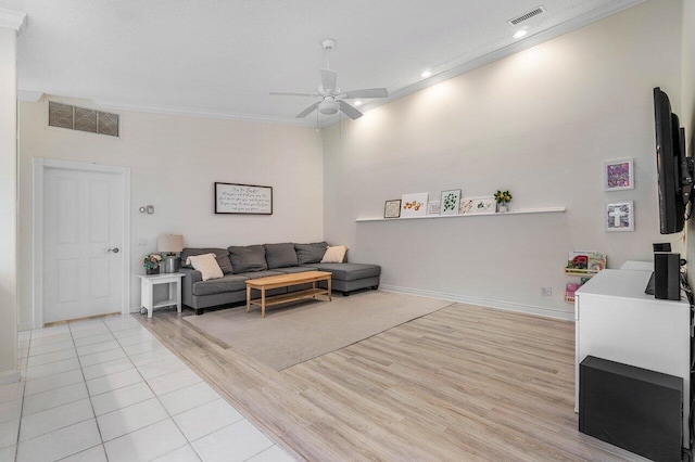 living room with ceiling fan, crown molding, light wood finished floors, and visible vents