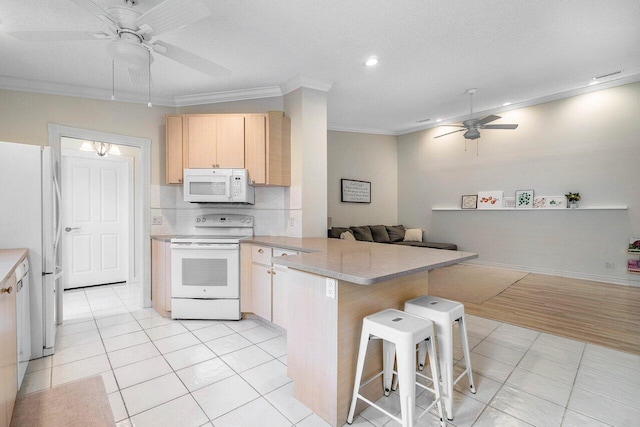kitchen featuring a peninsula, light brown cabinetry, crown molding, ceiling fan, and white appliances