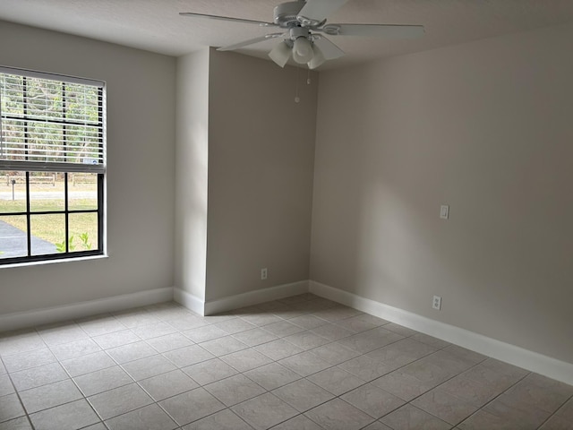 empty room with light tile patterned floors, ceiling fan, and baseboards