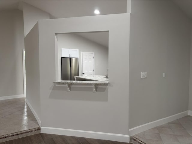 corridor with vaulted ceiling, baseboards, recessed lighting, and light wood-type flooring