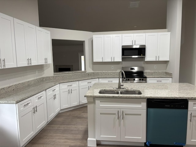 kitchen featuring stainless steel appliances, a sink, white cabinetry, and light stone countertops